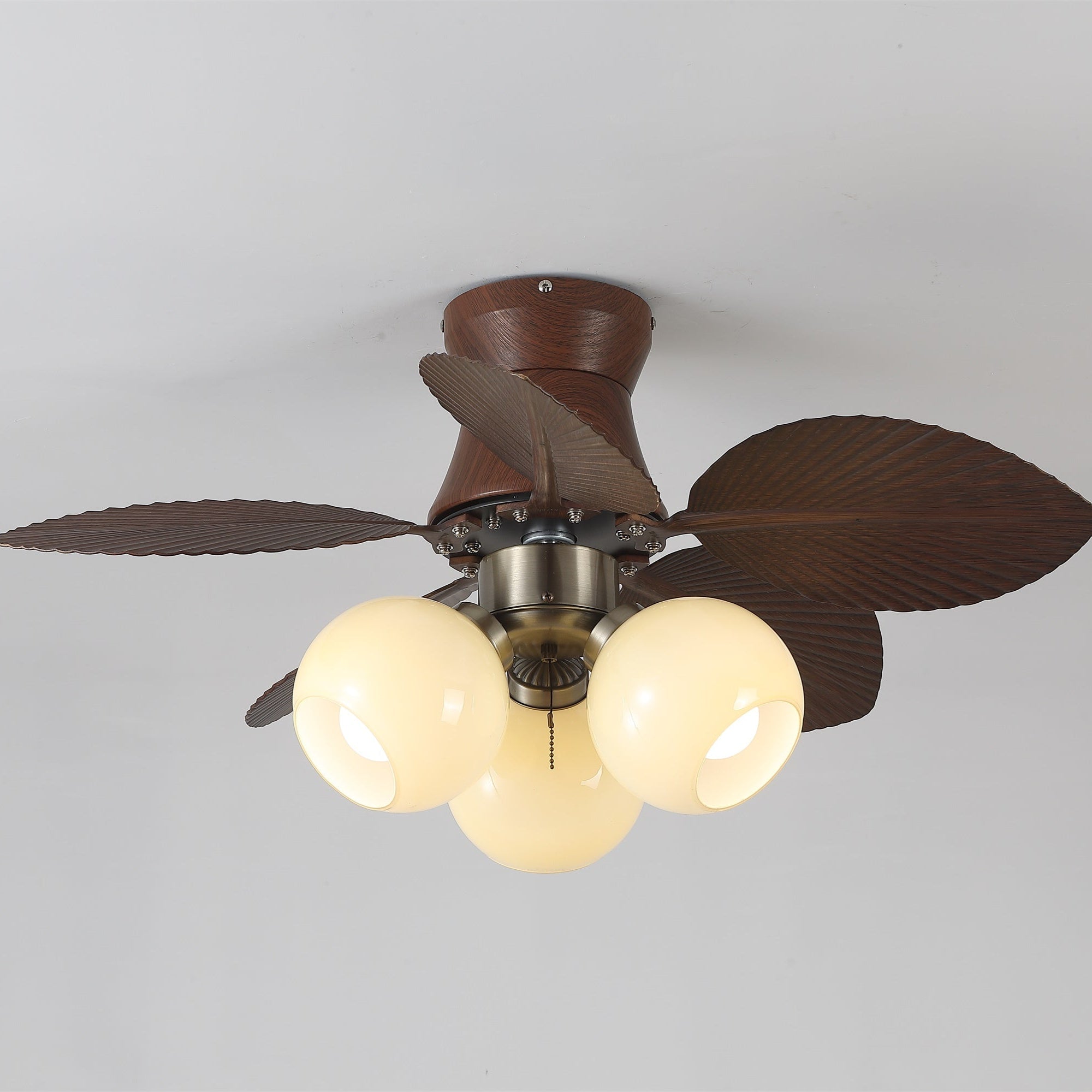 Primo piano del paralume in vetro e del corpo motore del ventilatore da soffitto con luce Walden Oak